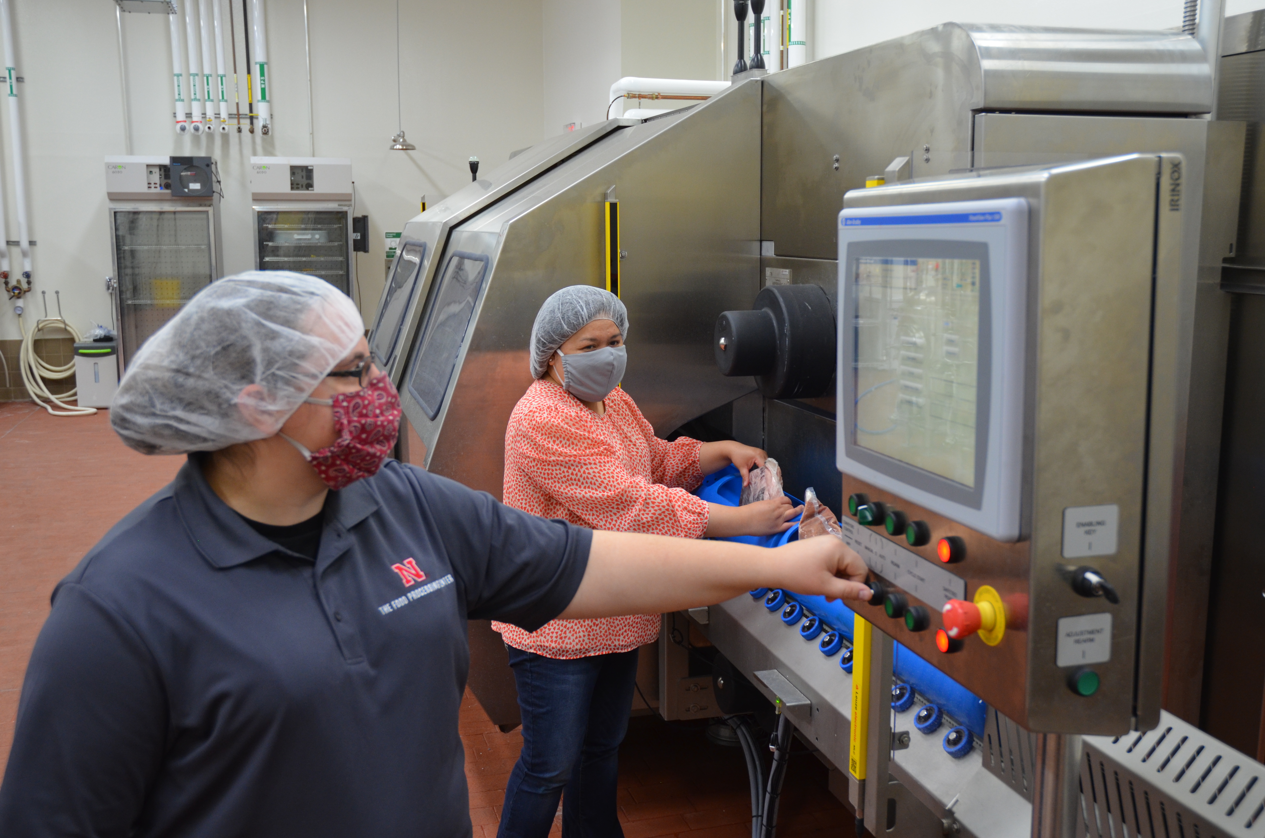 Two people working with high pressure processing equipment