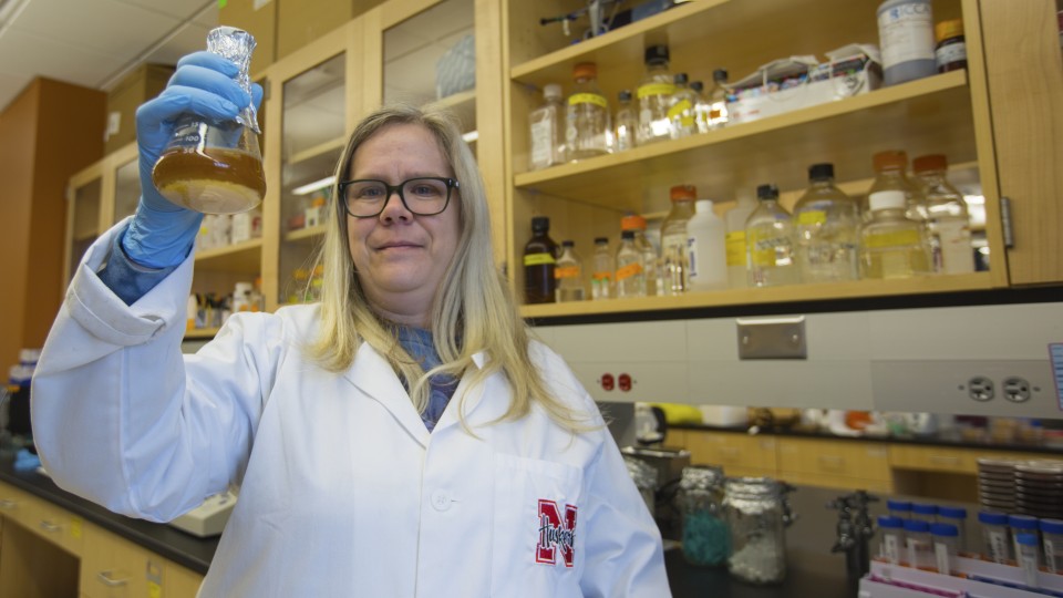 Dr. Heather Hallen-Adams hold a flask in a lab